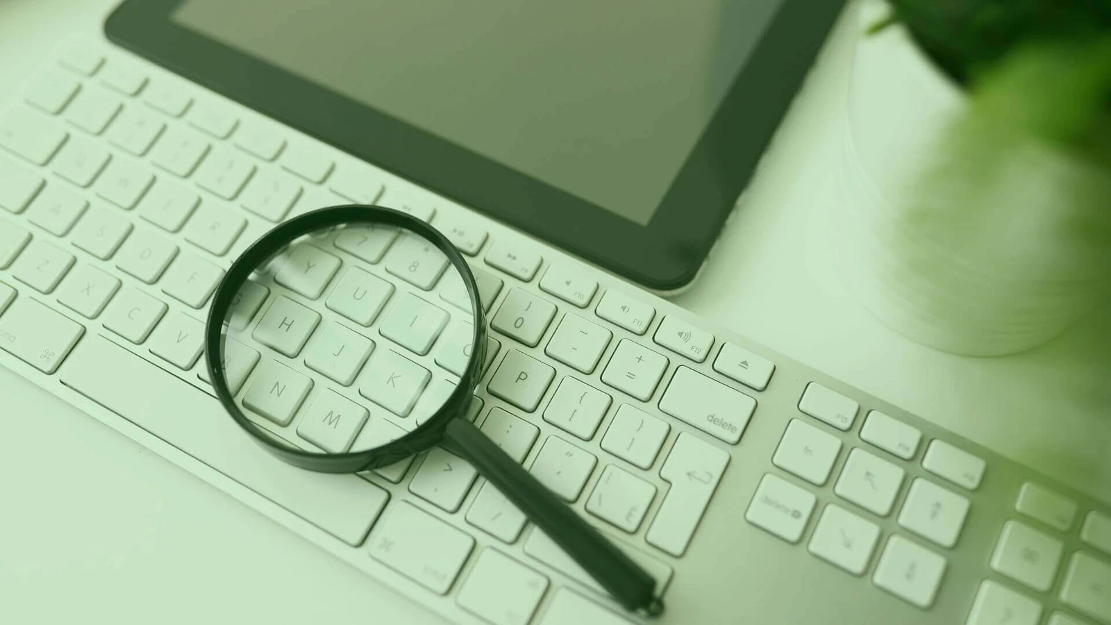 Em quais ações investir: lupa sobre um teclado para ilustrar a pesquisa de empresas.